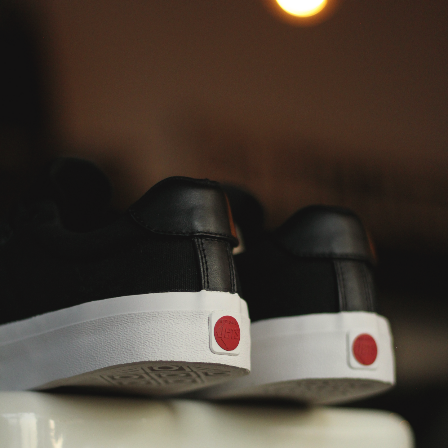 Black shoes with white soles and red accents on a white surface.