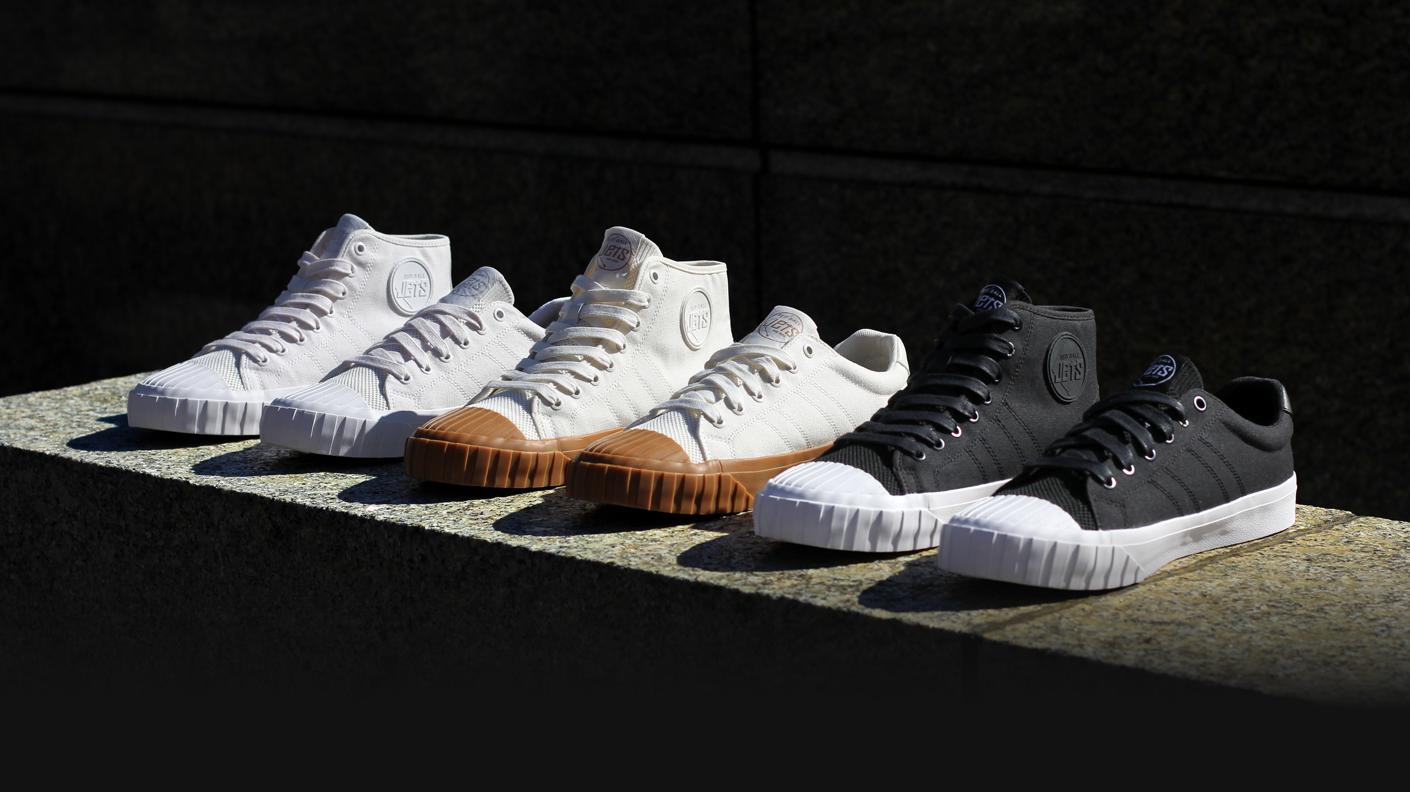 Four Red Ball Jets Legacy Collection sneakers lined up on a stone ledge against a dark wall.