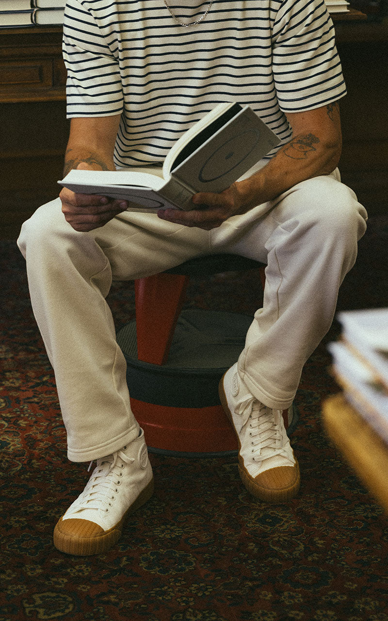 Off-white Red Ball Jets' high-tops on the feet of a white model reading a book in a book store
